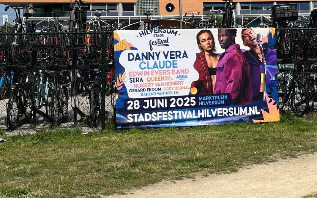 Spandoek van het Hilversum Stadsfestival aan een hek bij de fietsenstalling