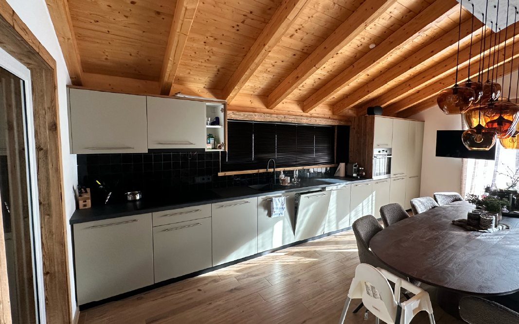 Keuken met lichtgrijze fronten in interieurfolie onder een houten plafond