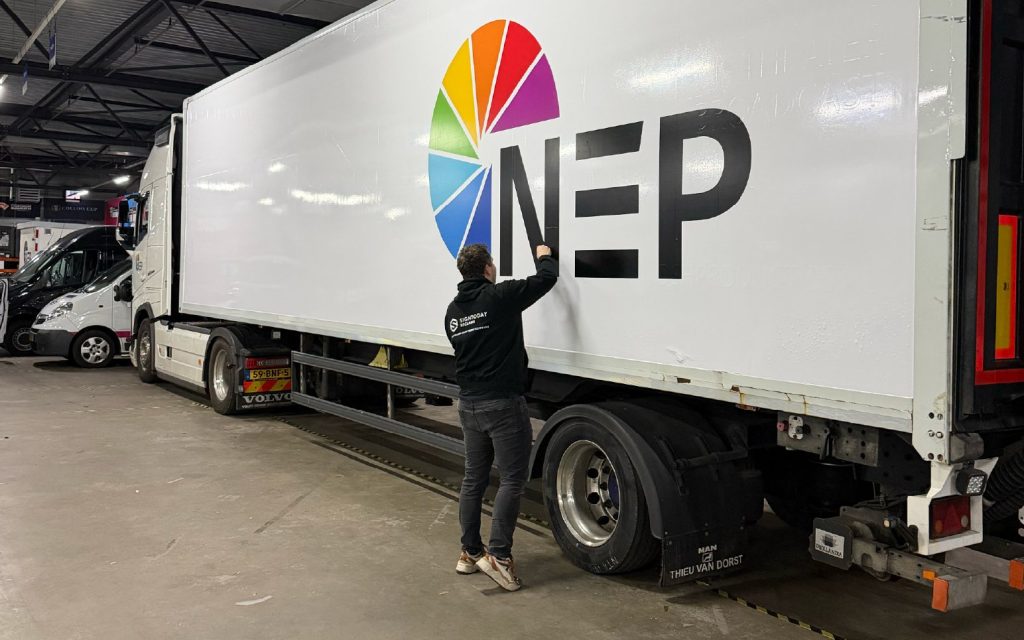Monteur van Signtoday brengt het NEP-logo aan op een witte trailer
